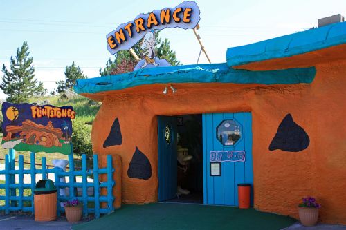 Colorful entrance to a Flintstones-themed attraction, featuring a blue door and orange stone-like walls.
