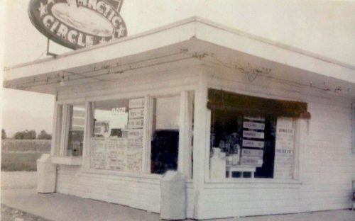 A vintage diner called "Arctic Circle" with a sign, large windows, and a menu displayed outside.