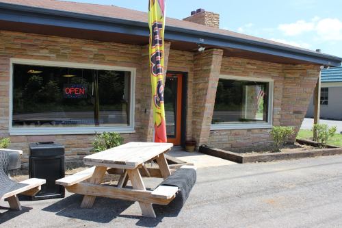A stone building with large windows, an "OPEN" sign, and a picnic table outside on a sunny day.