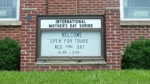 Sign for the International Mother's Day Shrine, welcoming visitors for tours Wednesday to Saturday, 10:00 AM to 3:00 PM.