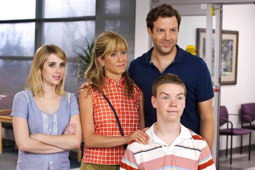 A group of four people poses together, smiling in a bright, modern office setting.