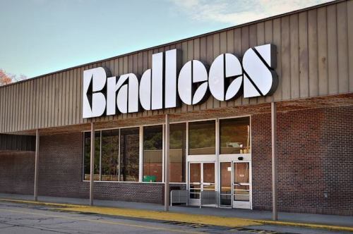 Exterior of a Bradlees store with large signage and glass entrance, set against a clear sky.