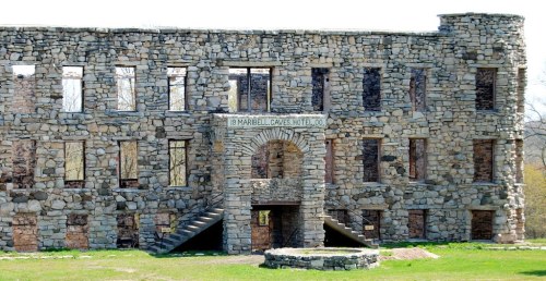 Ruins of the Maribell Caves Hotel, featuring stone walls and arched entrance, surrounded by grass.