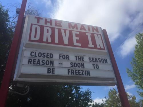 Sign outside a drive-in reads: "CLOSED FOR THE SEASON REASON -- SOON TO BE FREEZIN." Blue sky in the background.