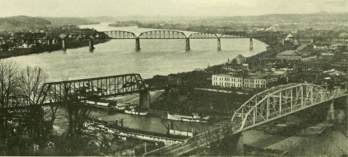 A historic view of a river with multiple bridges and boats, surrounded by buildings and trees.