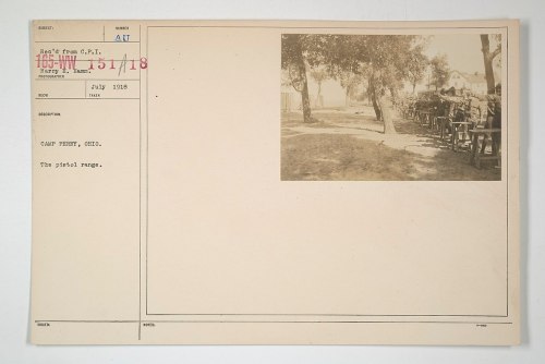 A historic photo of a pistol range at Camp Perry, Ohio, taken in July 1918, featuring wooden shooting benches.