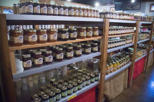 Shelves filled with various jars of preserves, sauces, and condiments in a well-organized store display.