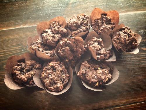 A cluster of chocolate muffins in brown paper liners, arranged on a wooden surface.