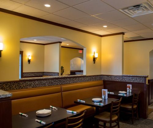 Cozy restaurant interior featuring booths, tables, and warm lighting with a neutral color scheme.