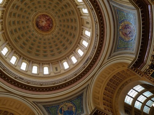 View of a grand dome interior with intricate designs and stained glass windows.