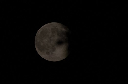 A close-up view of the moon partially illuminated against a dark night sky.