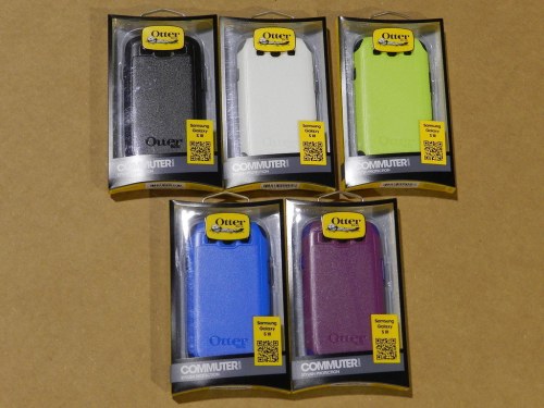 Six OtterBox Commuter phone cases in various colors, displayed in packaging on a brown background.