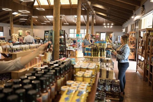 A busy store interior with wooden beams, shelves filled with products, and customers browsing and shopping.