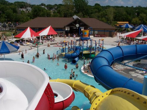 A vibrant water park scene with colorful slides, a pool, and families enjoying the sun and water activities.