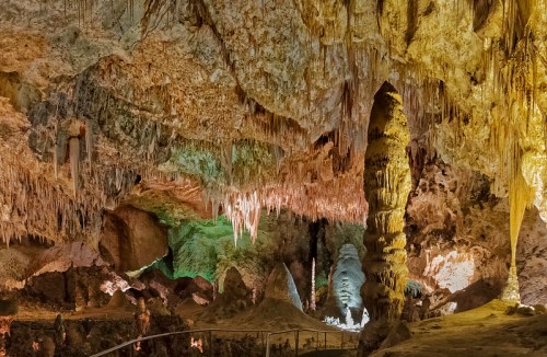 A stunning cave interior with colorful lighting highlighting stalactites and stalagmites.