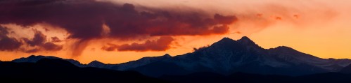 Silhouette of mountains against a vibrant sunset sky with clouds in shades of orange and purple.