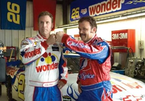 Two race car drivers in colorful racing suits pose with fists bumping in a garage, with a race car in the background.