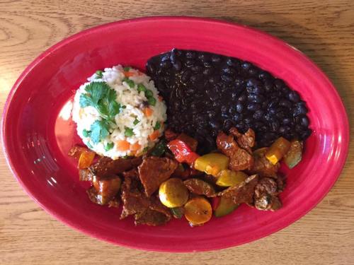 A vibrant plate featuring rice with vegetables, black beans, and a mix of sautéed peppers and meat.