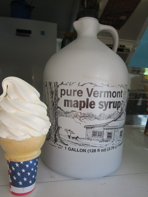 A gallon jug of pure Vermont maple syrup next to a soft serve ice cream cone in a patriotic cup.