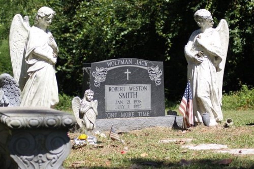 Gravestone of Robert Weston Smith, flanked by angel statues and small flags, in a serene cemetery setting.