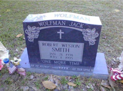 A gravestone with the name "Wolfman Jack" and "Robert Weston Smith," featuring a cross and decorative elements.