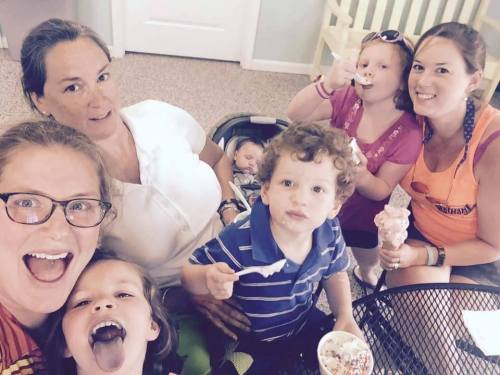 A group of adults and children enjoying ice cream together, smiling and having fun in a cozy indoor setting.