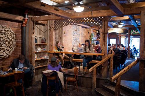 Cozy café interior with wooden beams, patrons reading and working at tables, and a warm, inviting atmosphere.