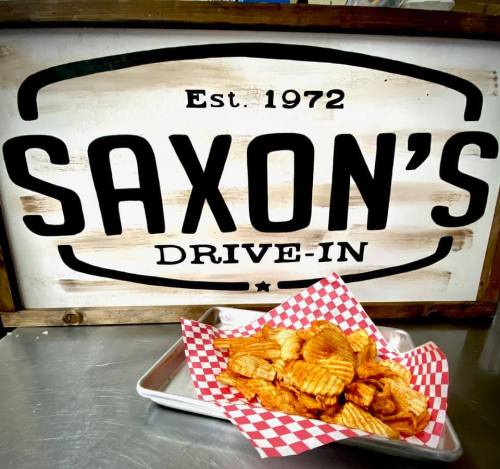 A tray of crispy, wavy potato chips in front of a sign that reads "Saxon's Drive-In, Est. 1972."