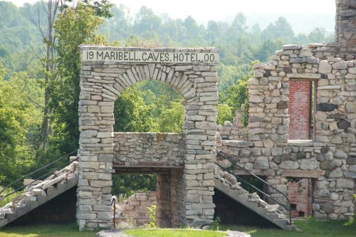 Ruins of the Maribell Caves Hotel, featuring a stone archway and steps, surrounded by lush greenery.