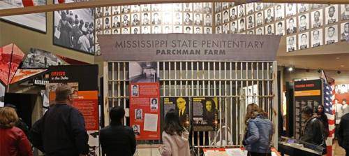 Visitors explore an exhibit featuring the history of Parchman Farm, with photos and information on the walls.