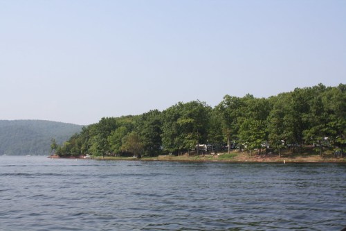 A serene lake scene with lush green trees lining the shore under a clear blue sky.