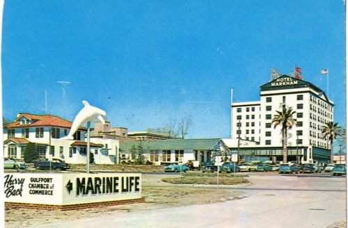 A vintage postcard showing Hotel Markham and a sign for Marine Life in Gulfport, with palm trees and classic cars.