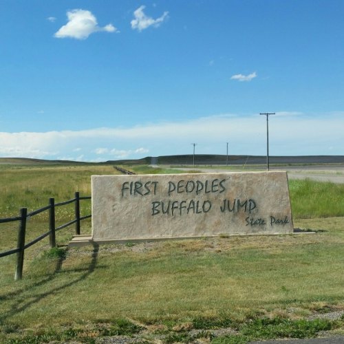 Sign for First Peoples Buffalo Jump State Park, with a clear blue sky and open landscape in the background.