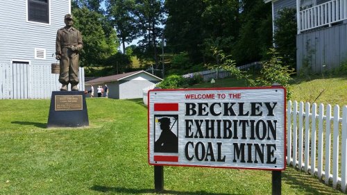 A statue of a coal miner stands beside a sign welcoming visitors to the Beckley Exhibition Coal Mine.