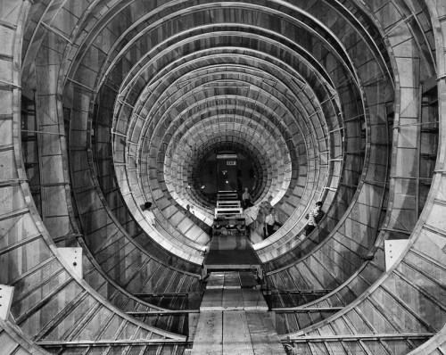 Interior view of a large, circular tunnel structure with a spiral design, featuring workers and scaffolding.