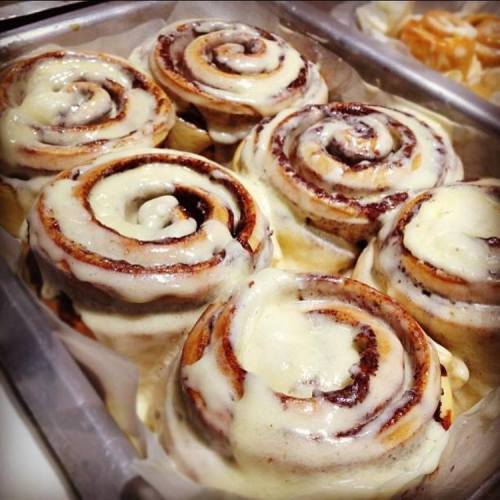 Freshly baked cinnamon rolls drizzled with creamy icing, arranged in a tray.