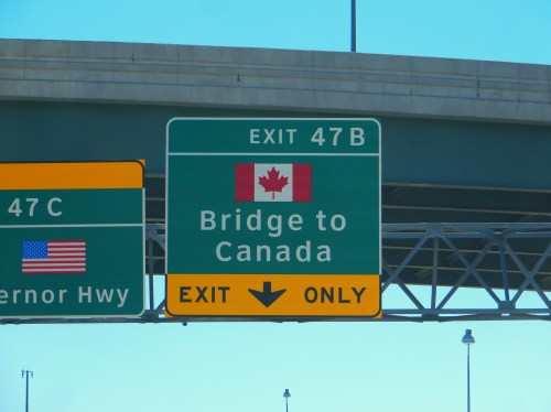 Green highway sign indicating "Exit 47B: Bridge to Canada" with a Canadian flag and "Exit Only" arrow.