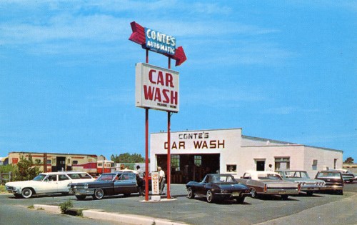 A vintage car wash with several classic cars parked outside, featuring a large sign that reads "Conte's Car Wash."