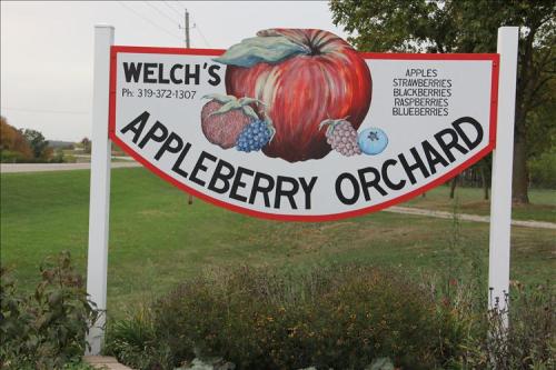 Sign for Welch's Appleberry Orchard featuring a large apple illustration and listing various fruits available.