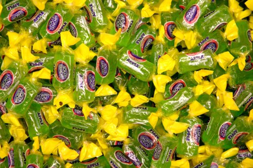 A colorful pile of green apple-flavored candies wrapped in yellow and blue packaging.