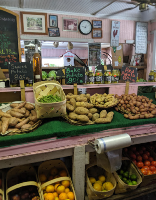 A market display featuring various types of potatoes, including sweet and red potatoes, on a colorful counter.