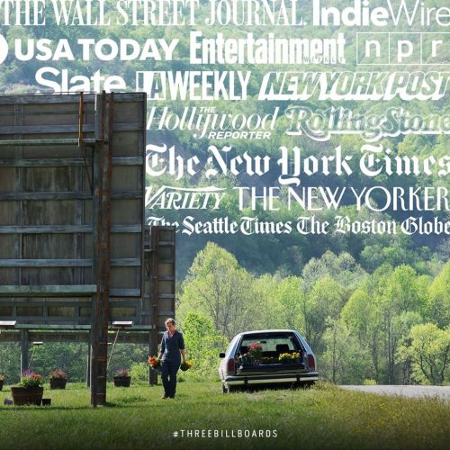 A person walks towards a car near billboards featuring various media outlet names in a scenic landscape.