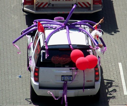 A decorated white SUV with purple balloons and streamers, celebrating a festive event.