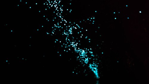 A dark background with scattered glowing turquoise dots resembling stars or particles in motion.