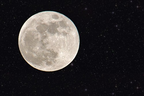 A bright full moon against a dark starry sky, showcasing its craters and surface details.
