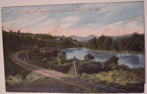 A vintage postcard depicting a winding river with mountains in the background and a railway track along the shore.