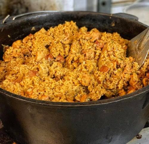 A large pot filled with flavorful, golden-brown rice mixed with pieces of chicken.