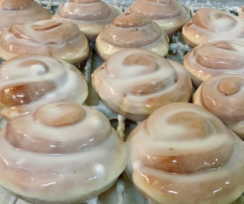 Freshly baked cinnamon rolls topped with creamy icing, arranged neatly on a cooling rack.
