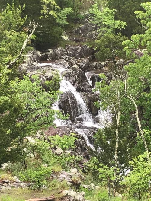 A serene waterfall cascading over rocky terrain, surrounded by lush green foliage and trees.