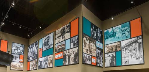 A gallery wall featuring large framed historical photographs in black and white, with colorful accent panels.